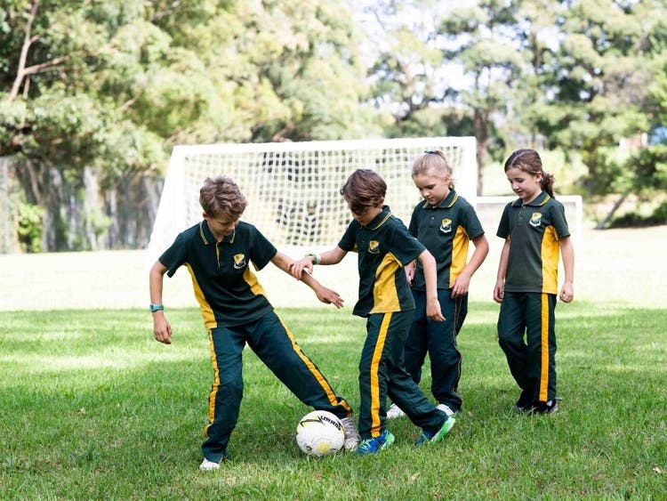 Two boys and two girls playing soccer in their sport uniform