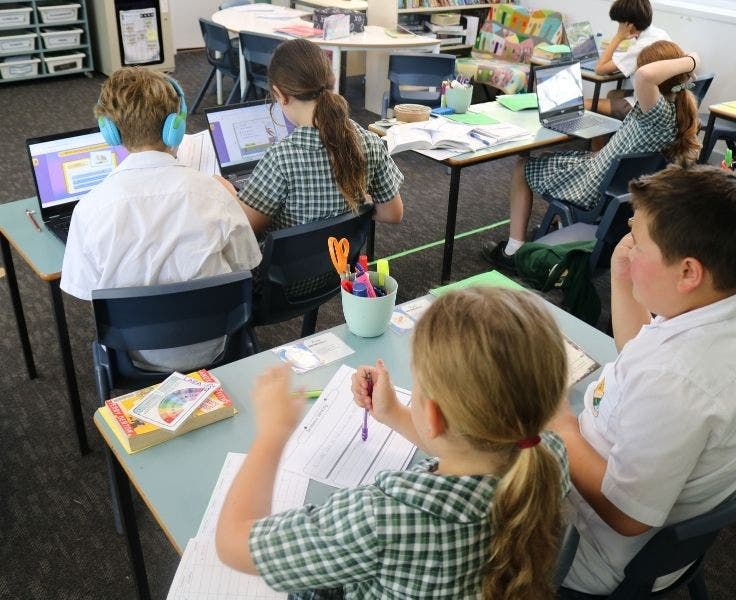 Students in a classroom setting at desks and laptops