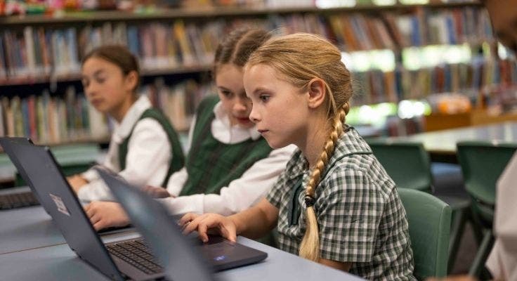 Three students using laptops in the classroom